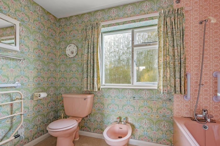 Original bathroom including green and pink bathroom tiles and wallpaper of the 1970s house in Salcombe, Devon. See SWNS story SWLNhouse. An incredible 'time warp' 1970s home with original patterned wallpaper, lino and apricot tiles has gone on the market - for £1million. The four bedroom property was originally built in the seventies and has been with the same owners for almost 40 years. The house is described as being "ready for modernisation" but some 70s fans may want to leave the decor exactly as it is.