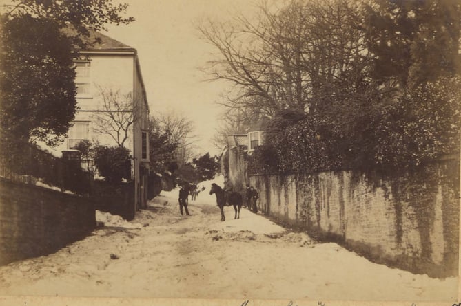 March 1891. Looking north up Fore Street, Kingsbridge, with Knowle House garden wall on right. People in road after the blizzard.  Mrs Haynes Series
