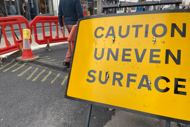 Official signs warning pedestrians of the uneven pavement ahead