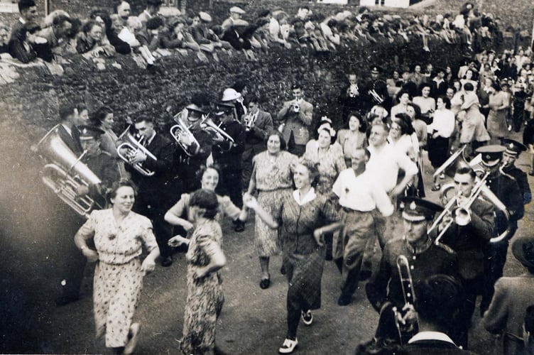 The Floral Dance in Malborough being watched by people over the wall