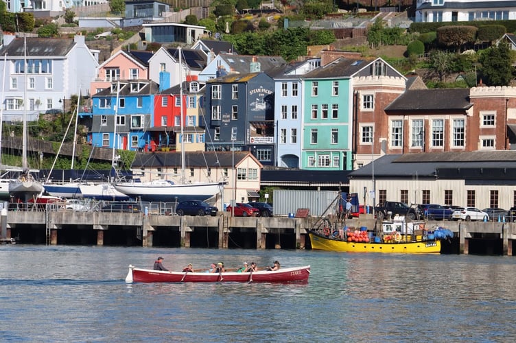 Rowers pass in front of the pastel-shades of Kingswear