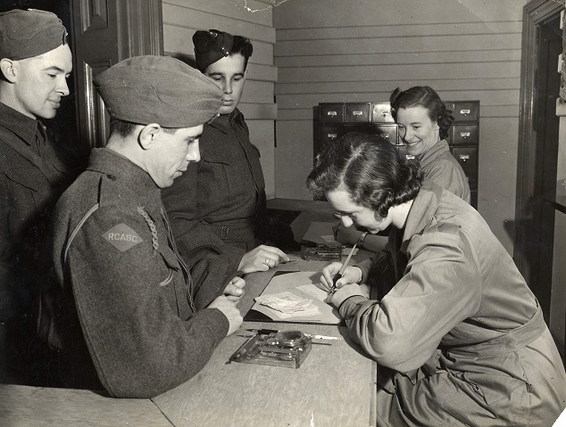 Three Canadian soldiers registering at the Beaver Club in London where soldiers on leave were looked after. 
January 1942. 
