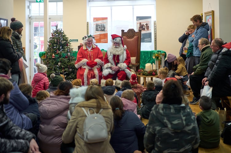 Children gather around Santa for a story and early Christmas presents.