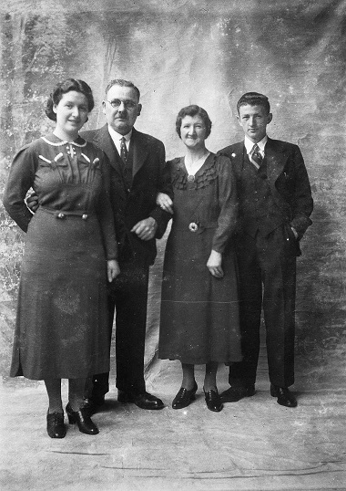 Family photograph with parents and two children, all standing.