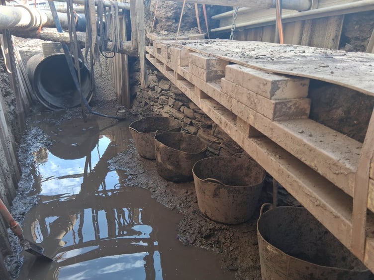 Original side wall of the old culvert emerging, with buckets lined up ready to be filled and the encased electric cables that have been sitting underground for more than 80 years.